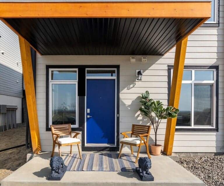 Covered front entry with blue door and two chairs at a 1-bedroom suite in Seton, Calgary