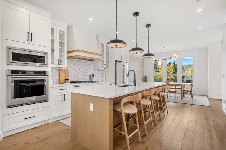 Kitchen with white cabinets, large wood island and bar stools in a 3-bedroom Calgary home