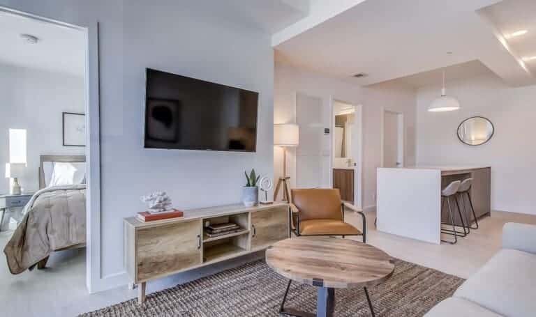 Living room with wood coffee table and kitchen island in a 1-bedroom Calgary walk-out suite