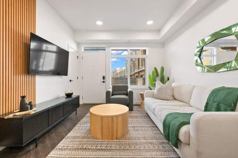 Living room with white sofa, wood slat wall and round coffee table in a 1-bedroom Calgary suite