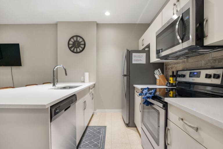 Kitchen with white counters and stainless steel appliances in a Cochrane suite near the Rocky Mountains