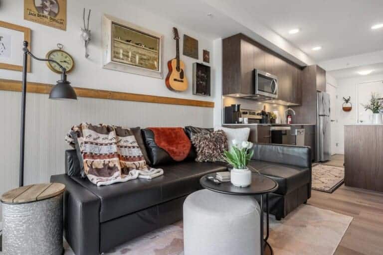 Western-themed living room with leather sofa, guitar wall decor and kitchen in a Calgary condo