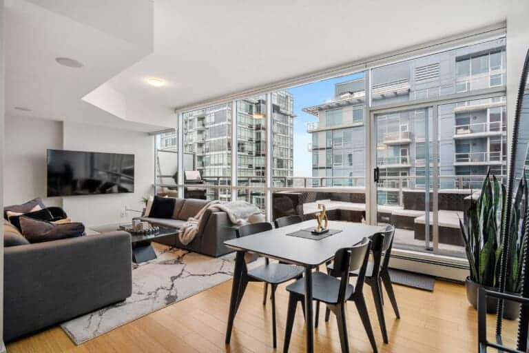 Penthouse living and dining area with glass walls opening to a terrace near Stampede Park, Calgary