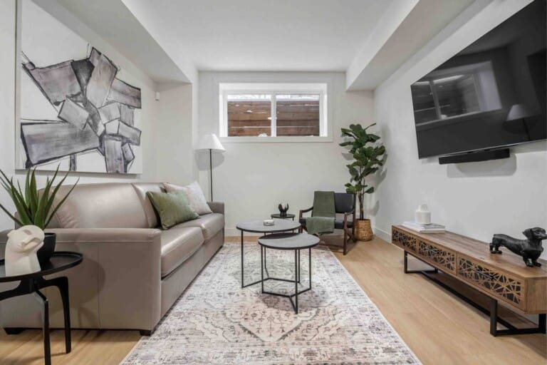 Living room with grey sofa and wall-mounted TV in a 2-bedroom Calgary suite near the University of Calgary
