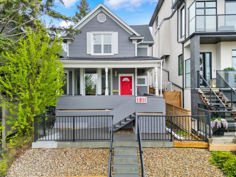 Exterior of a grey character home with red door and front porch in Calgary