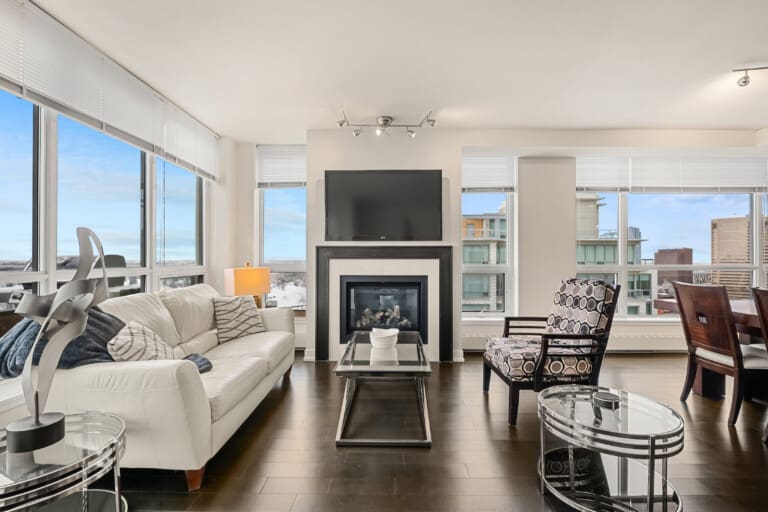 Living room with white sofa, fireplace and river views in a 2-bedroom Calgary condo