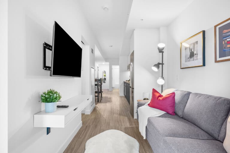 Living room with grey sofa and hallway in a 1-bedroom central Calgary condo