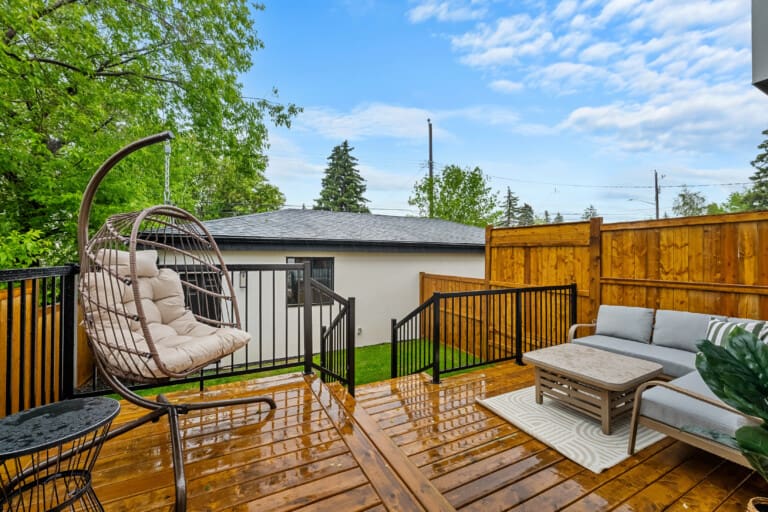 Sunny wooden deck with outdoor sofa and hanging egg chair at a 3-bedroom Calgary home