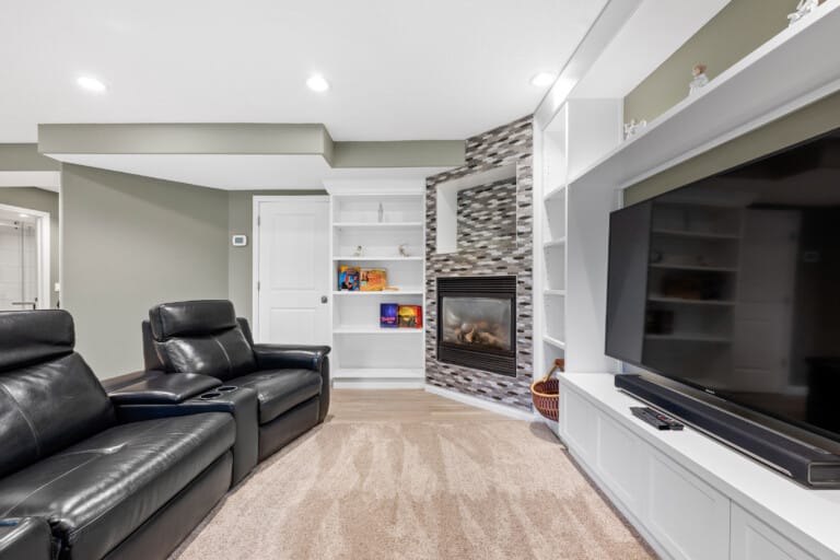Living room with leather recliners, fireplace and large TV in a private Evergreen suite near Fish Creek, Calgary